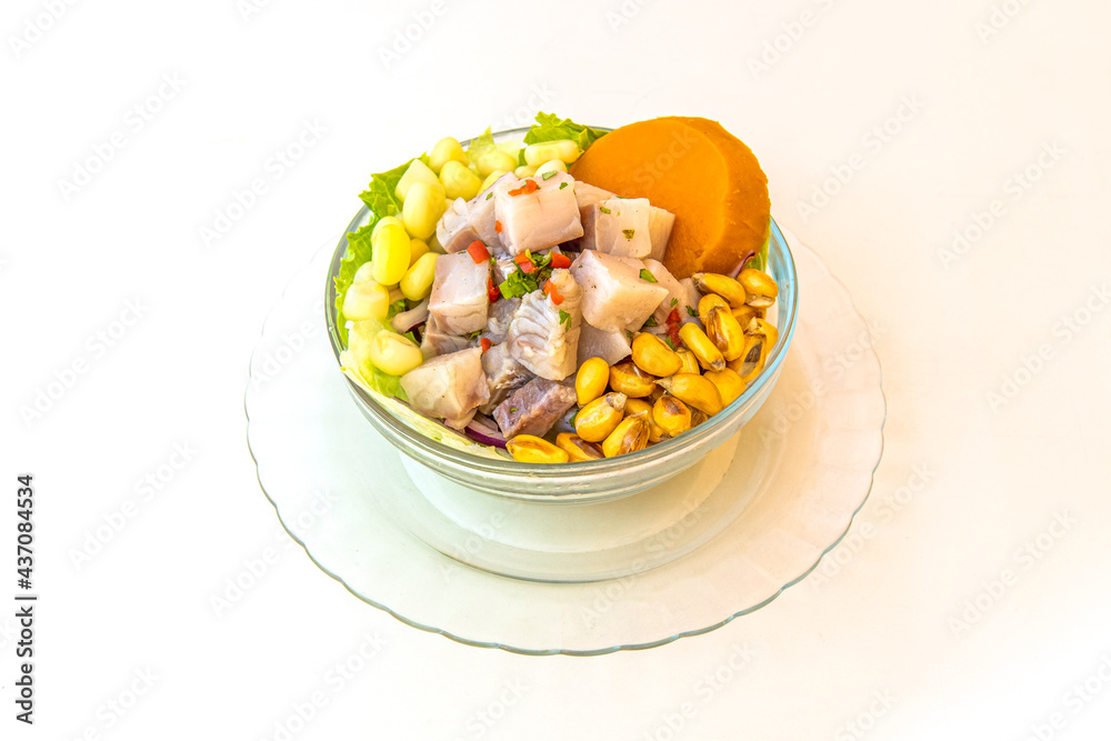 Glass bowl filled with Peruvian fish ceviche with cancha, sweet potato and lettuce