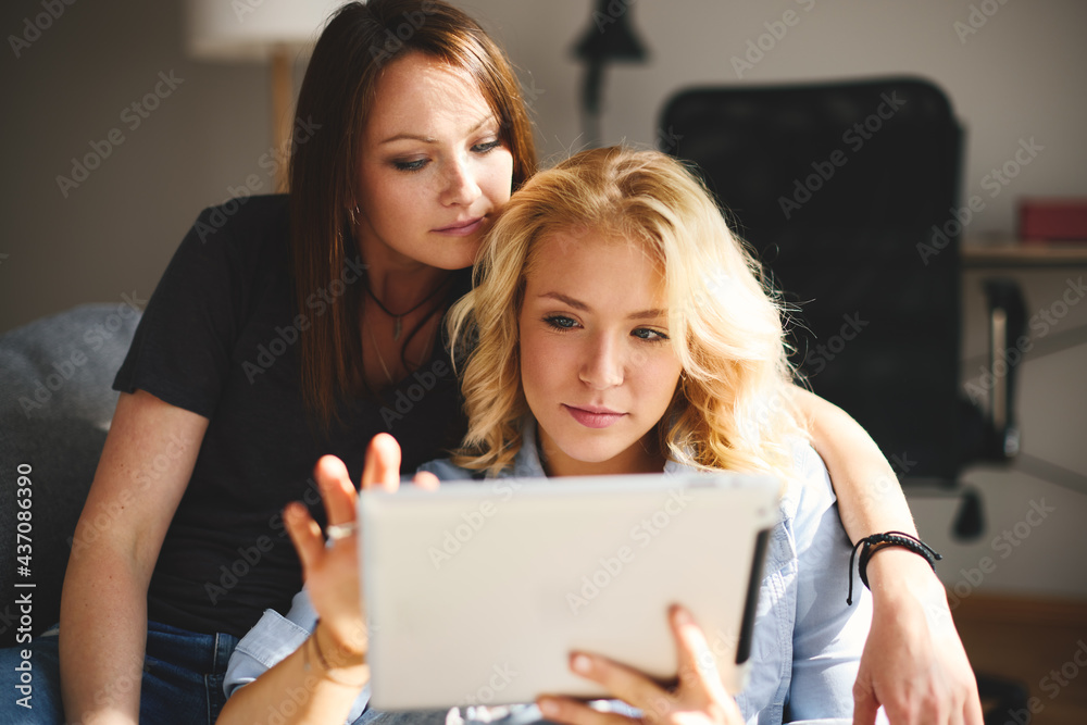 Two young women sitting on sofa and use a digital tablet Two young women sitting on sofa and use a digital tablet