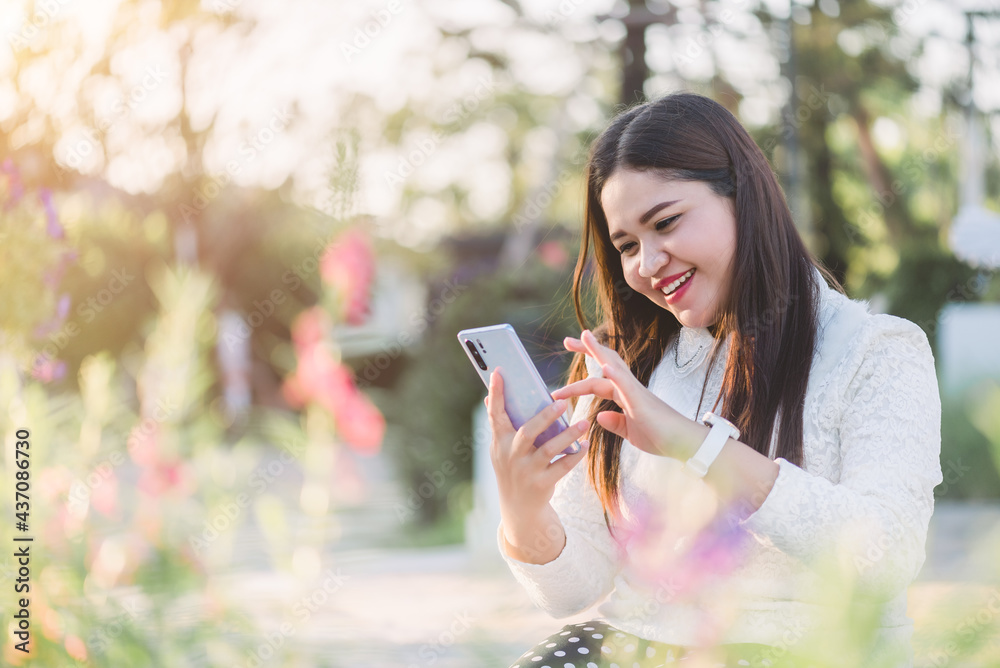 Young Asian woman using social network via smart mobile phone at the park ,lifestyle and daily life concept Young Asian woman using social network via smart mobile phone at the park ,lifestyle and daily life concept
