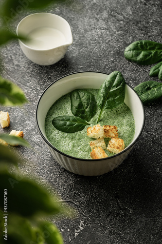 cream soup of green fresh spinach with cream and croutons for decoration. on a dark copyspace background, For menus and articles with recipes