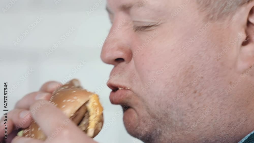 A man with pleasure bites a bun with a cutlet. Slow motion. Close-up. A man with pleasure bites a bun with a cutlet. Slow motion. Close-up.