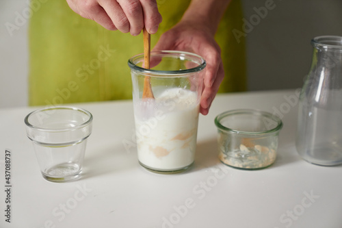 Wallpaper Mural Male beaker chef in green apron mixing milk, sugar, fresh wild yeast and flour all together in transparent glass as yeast dough starter ingredients on white table. High quality photo Torontodigital.ca