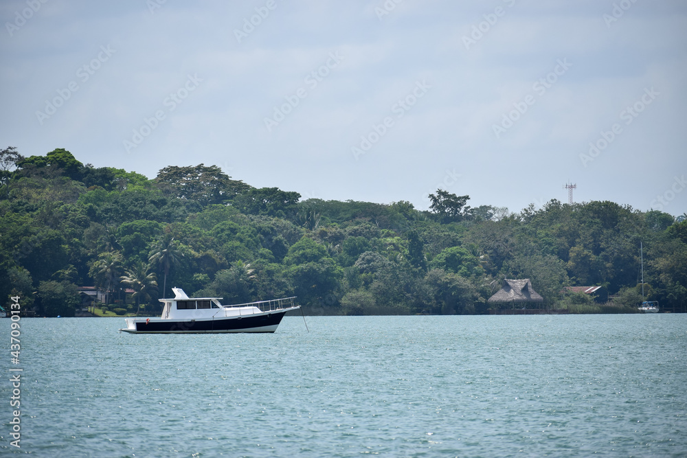 Lancha navegando en el Lago de Izabal, rodeado de naturaleza verde, departamento de Izabal en Guatemala Lancha navegando en el Lago de Izabal, rodeado de naturaleza verde, departamento de Izabal en Guatemala