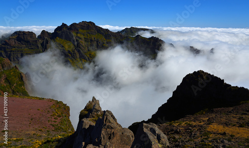  Pico do Areeiro Madeira peaks among clouds with blue sky above.
