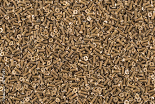 Old brass countersunk head screws with a phillips head screwdriver. Texture, background of screws. Gold color screws. Brass metal