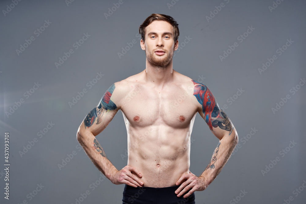 athletic man with pumped up abs tattoos on his arms