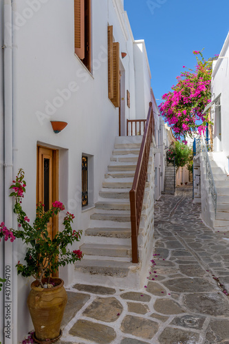 Fototapeta Naklejka Na Ścianę i Meble -  Traditional Cycladitic alley with a narrow street, whitewashed houses and a blooming bougainvillea in Parikia, Paros island, Greece