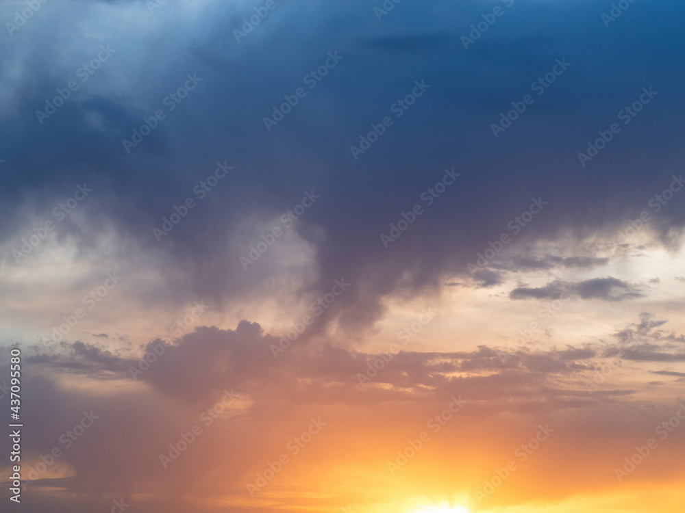 Bright multicolored sky-cloud background. The sun shines at the level of the horizon and colors the clouds in yellow and red tones