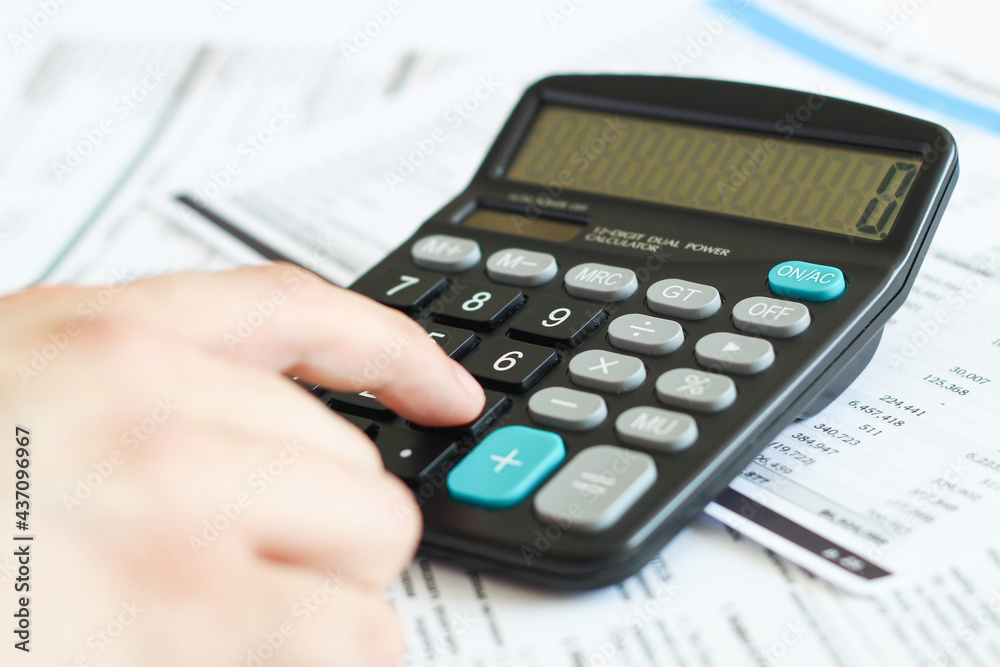 A businessman at an office desk counts on a calculator. business and finance A businessman at an office desk counts on a calculator. business and finance
