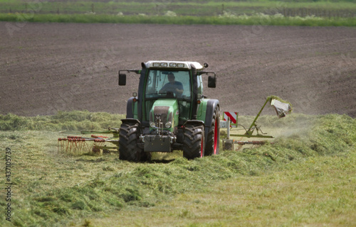 Photography Haymaking: tractor with tedder shaking mowed grass