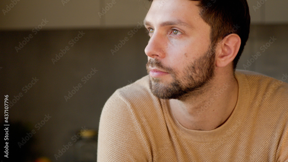 Fototapeta premium Young man in the kitchen close up. Handsome man thinking about idea
