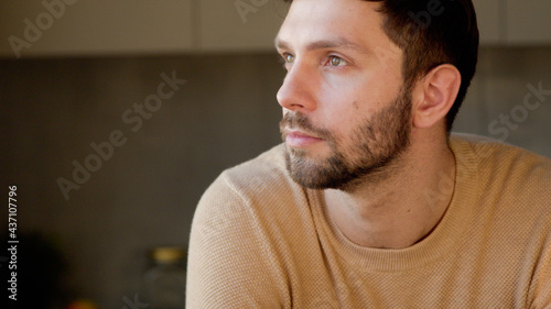 Young man in the kitchen close up. Handsome man thinking about idea