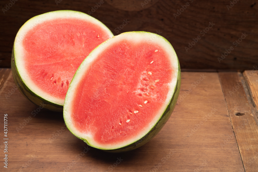 Freshly picked watermelon cut in half on a wood table Freshly picked watermelon cut in half on a wood table