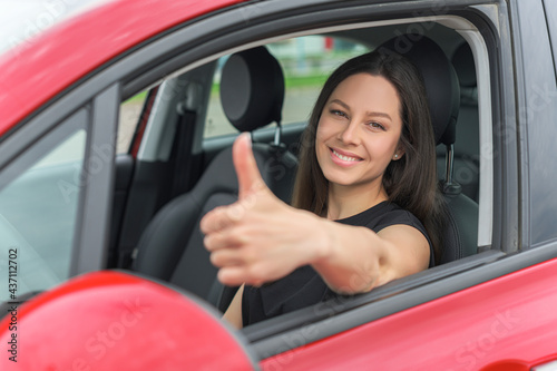 Car. Beautiful woman in the car shows thumbs up. Happy brunette in the car.