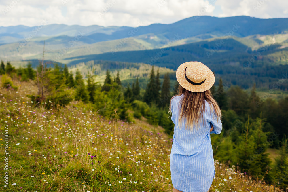 Traveling in spring Ukraine. Trip to Carpathian mountains. Woman tourist relaxing in flowers admiring view