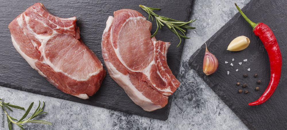 Raw pork steak on a dark background with herbs. Raw pork steak on a dark background with herbs.