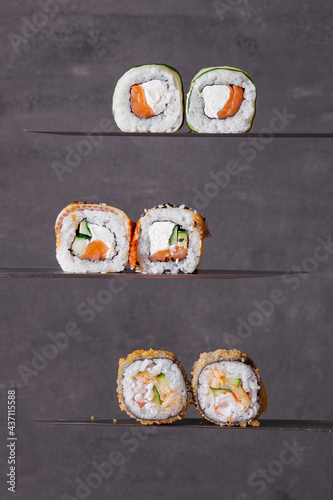 sushi rolls with salmon on a grey background on a knife close up