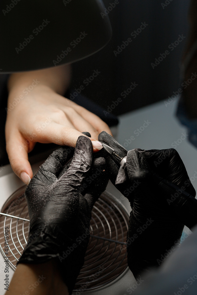 The manicurist makes a manicure with a saw in the salon. close-up