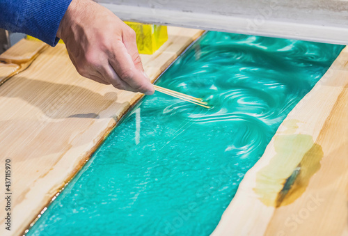 carpenter mixes epoxy to create a tracery on the kitchen table