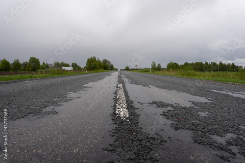 Wet damaged asphalt where there are many pits and small stones