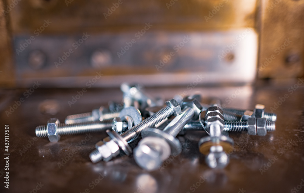Metal chrome bolts and nuts lie on the shiny metal surface of the machine Metal chrome bolts and nuts lie on the shiny metal surface of the machine