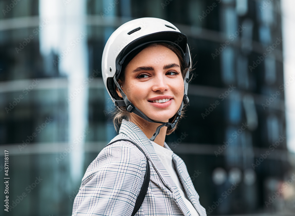 Portrait of a smiling woman wearing cycling helmet standing in front of an office building Portrait of a smiling woman wearing cycling helmet standing in front of an office building