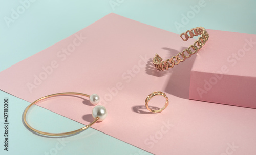 Chain shape and Gold with pearl bracelets and ring on pink and green paper