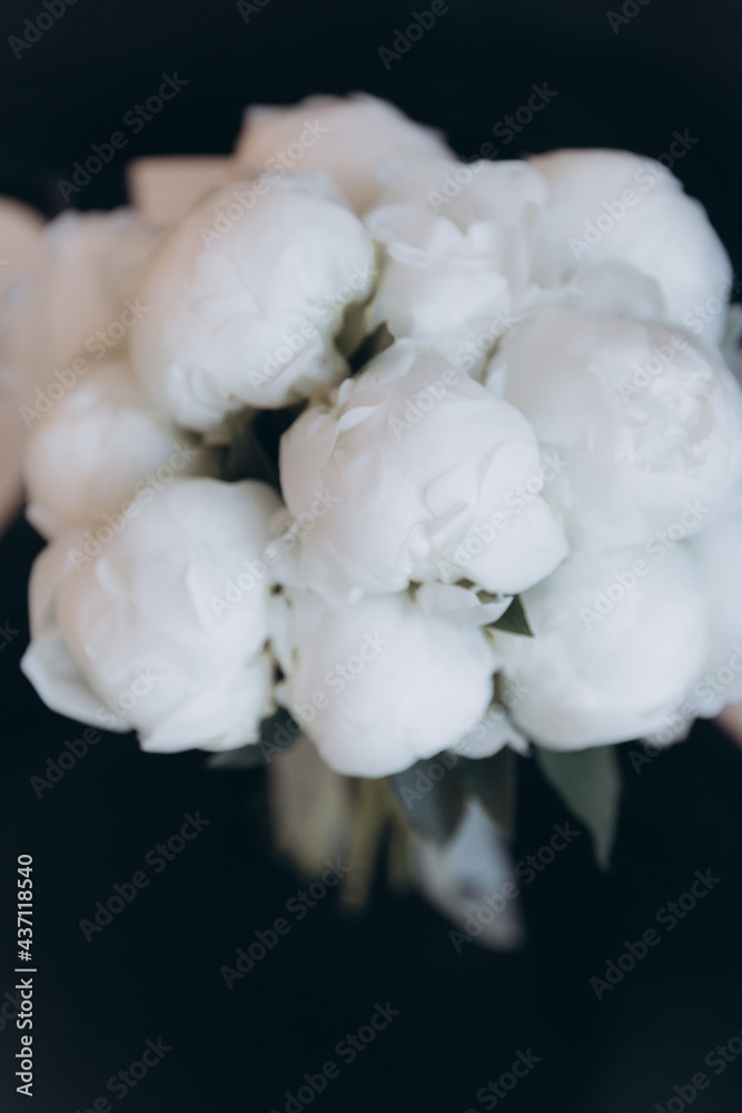 Beautiful white wedding bouquet of peonies on a black chair with a dress and a veil Beautiful white wedding bouquet of peonies on a black chair with a dress and a veil