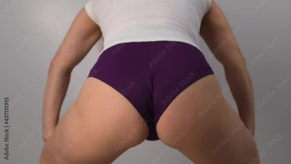 Close-up woman dancing twerk in shorts on a white background in the studio. Slow motion