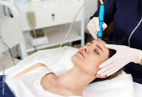 Close-up of a beautician using an aqua peel to clean and exfoliate a woman's face. Removal of skin slags in the pores using special equipment in hardware cosmetology.