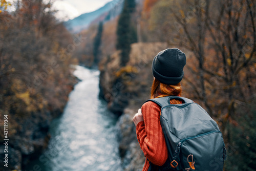 woman with backpack admires the river in the mountains nature travel