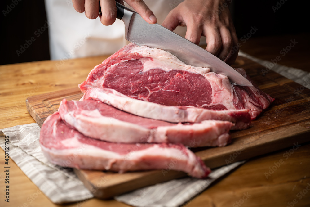 chef cutting block of ribeye beef steak