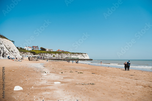 People chilling at Dumpton Gap bay with colourful wooden beach huts between Broadstairs and Ramsgate photo