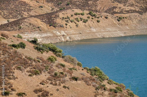 Beautiful shot of a reservoir surrounded by dry hills with few growing plants photo