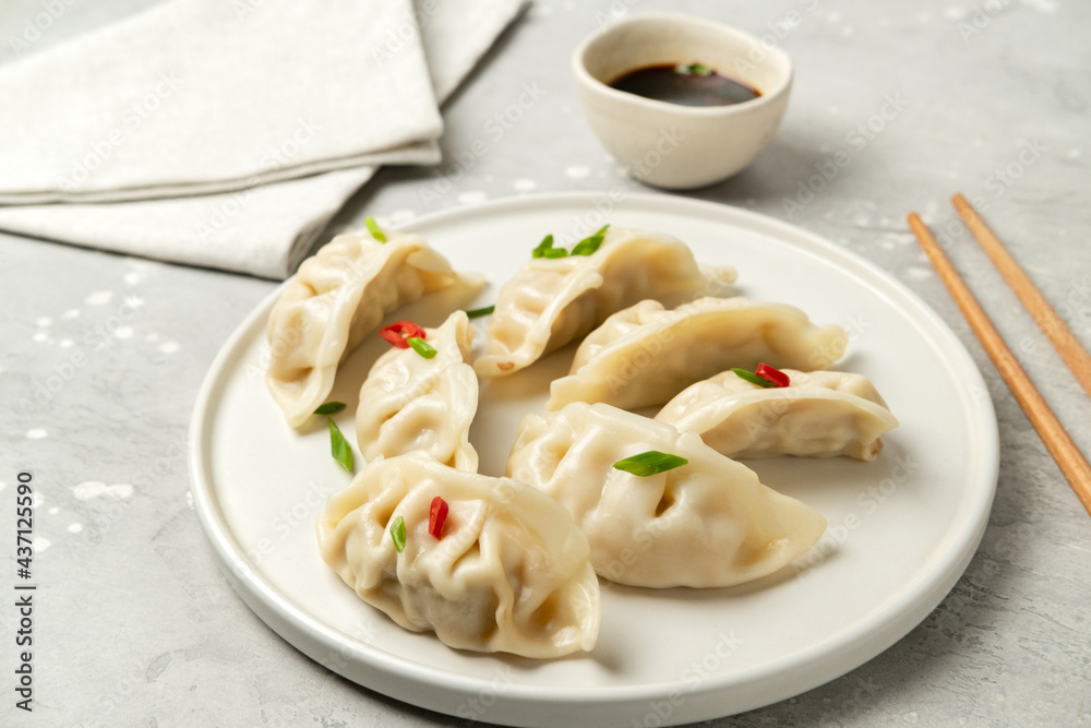 Jiaozi gyoza dumplings steamed on white plates with soy sauce and chili sauce. Food takeaway, home delivery