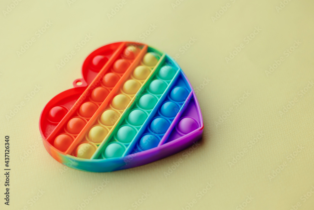 New fashionable toy for kids pop it. Antistress finger bubbles popular hit. Rainbow color heart shape silicone poppit. Relaxation simple dimple . Copy space top view colorful background. New fashionable toy for kids pop it. Antistress finger bubbles popular hit. Rainbow color heart shape silicone poppit. Relaxation simple dimple . Copy space top view colorful background.
