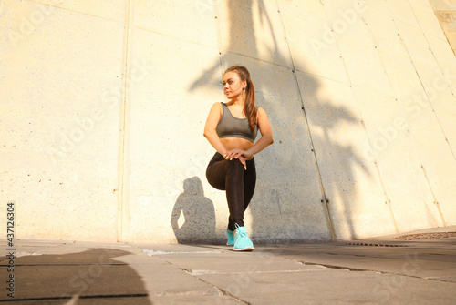 Fitness woman in sportswear doing workout over grey concrete wall. Outdoor.