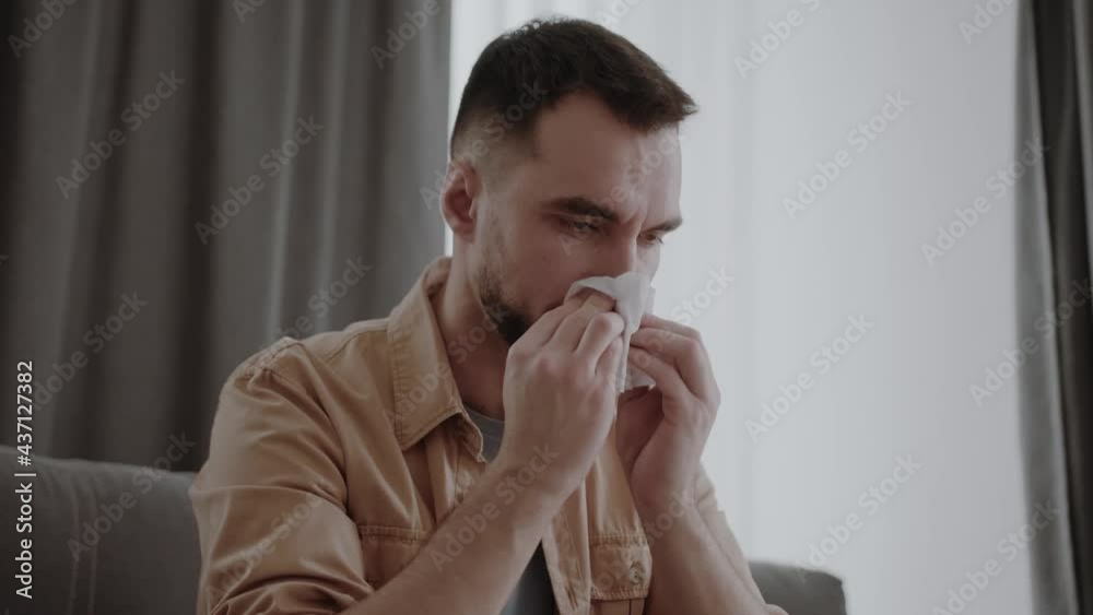 runny nose in a man holding tissue handkerchief blowing wiping his running nose. Headshot Male feels unwell caught influenza cold seasonal infection or having allergy concept runny nose in a man holding tissue handkerchief blowing wiping his running nose. Headshot Male feels unwell caught influenza cold seasonal infection or having allergy concept