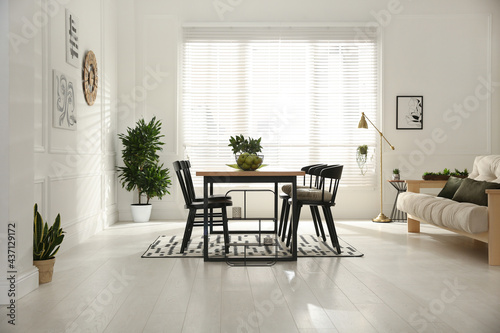 Stylish wooden dining table and chairs in room. Interior design photo