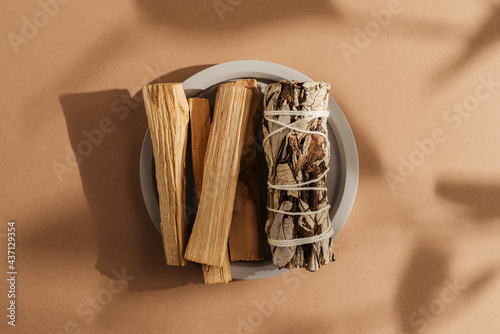 Branches of yerba santa, palo santo sticks tied in bunch on concrete plate, beautifully illuminated by sunlight. Set of incense for fumigation. Top view. Organic sacred tree incense from America