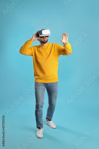 Man using virtual reality headset on light blue background © New Africa