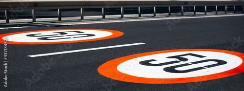 Two speed limit signs with 50 km per hour, painted on asphalting road. Panoramic banner view.