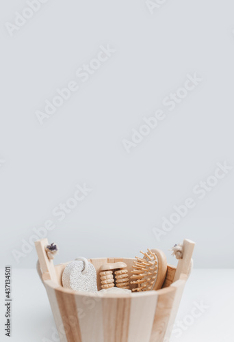 Close-up of some bath accessories in small wooden bucket against white studio background with copy space.