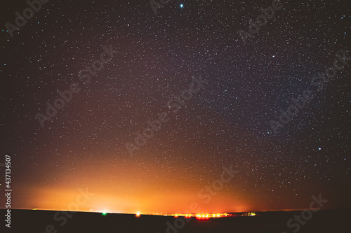 Night Sky Glowing Stars Background Backdrop. Colorful Sky Gradient. Sunset, Sunrise And Town Lights At Horizon. Colourful Night Starry Sky In Yellow Orange Colors