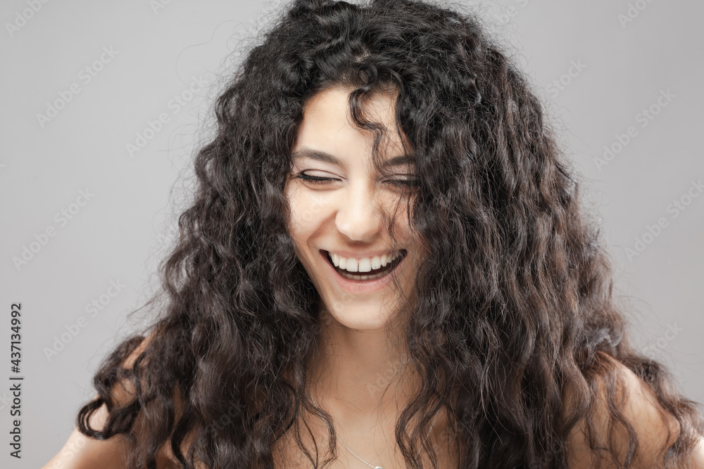 Beautiful brunette girl with long curly hair, studio portrait. Smiling face expression Beautiful brunette girl with long curly hair, studio portrait. Smiling face expression