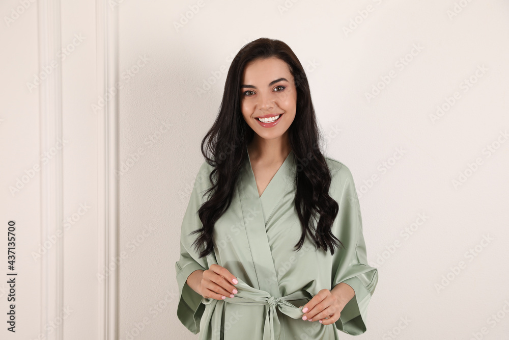 Pretty young woman in beautiful light silk robe near white wall Pretty young woman in beautiful light silk robe near white wall
