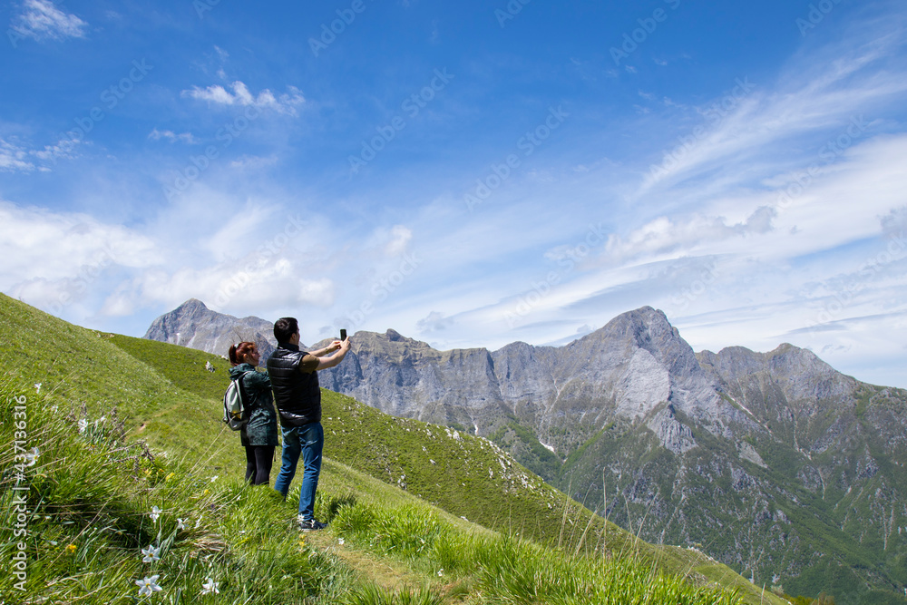 man and woman make photo with phone in flowered mountains of Apuan Alps