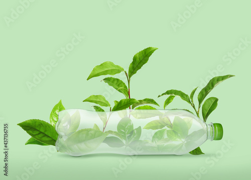 Bottle made of biodegradable plastic and leaves on green background photo