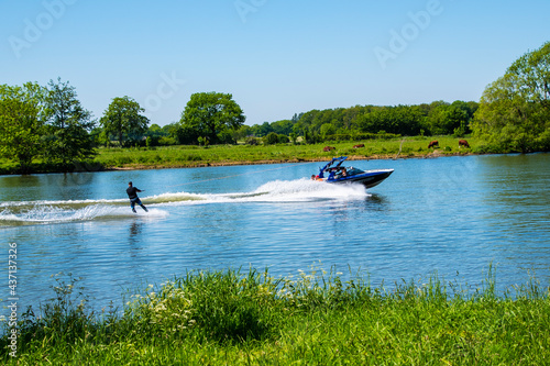 Wakeboarder on wakeboard landed in water surrounded by spray. A man rides water skis at high speed. Tense man wakeboarding in a lake. Wakeboarding is an extreme sport. Jumping from wave. photo