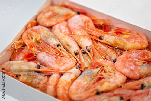 Frozen shrimps in a white carton packaging. Dry freezing of seafood delicacies